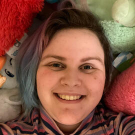 sam laying down on a bed made of squishables